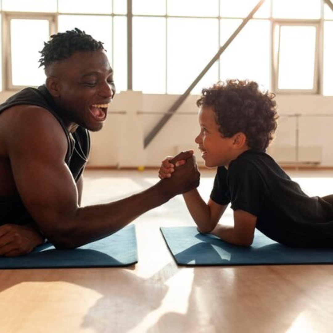 A young boy and an adult sharing a playful arm-wrestling moment