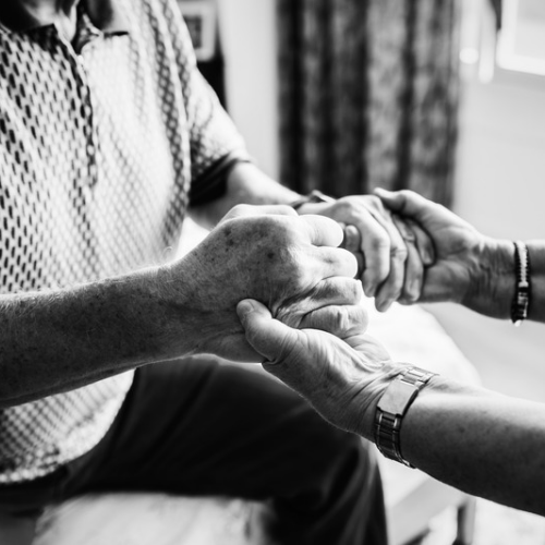 Two adults holding hands in support